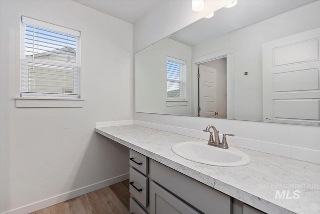 bathroom featuring baseboards, wood finished floors, and vanity