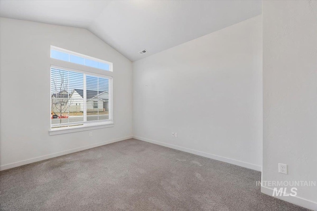 carpeted spare room featuring baseboards, vaulted ceiling, and visible vents