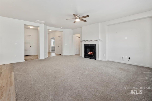 unfurnished living room with baseboards, a tile fireplace, carpet, and a ceiling fan