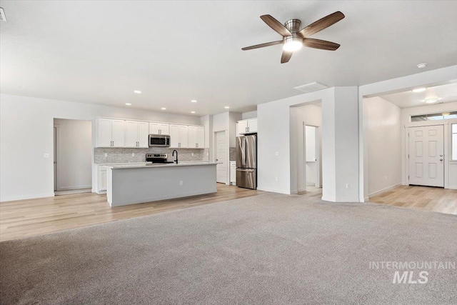 kitchen featuring light carpet, open floor plan, white cabinetry, and stainless steel appliances