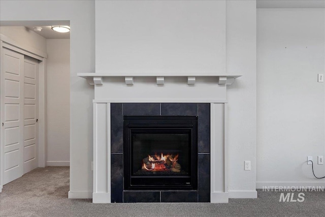 room details with a tile fireplace, carpet, and baseboards