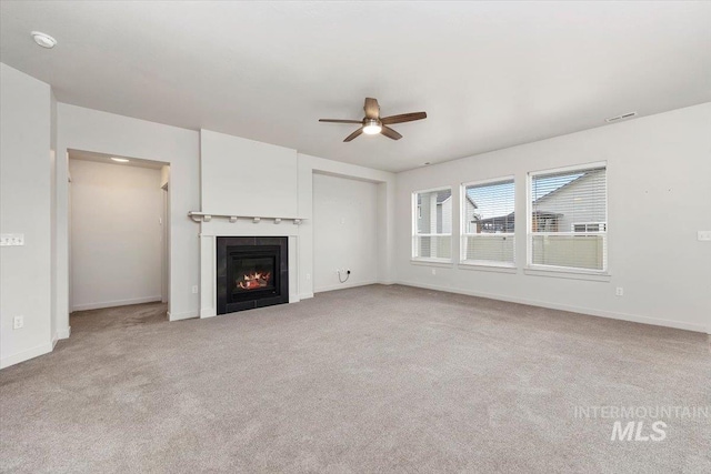 unfurnished living room featuring carpet flooring, visible vents, a tile fireplace, baseboards, and a ceiling fan