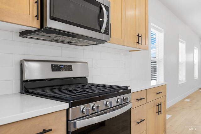 875 N 14th St, Payette, ID 83661 - kitchen featuring appliances with stainless steel finishes, light brown cabinetry, light wood-style flooring, decorative backsplash, and light countertops