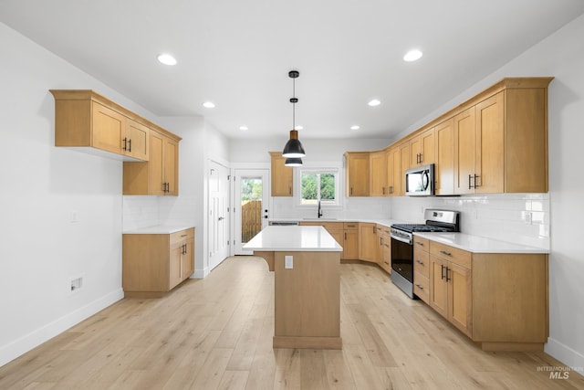 875 N 14th St, Payette, ID 83661 - kitchen with stainless steel appliances, a sink, decorative backsplash, a center island, and light wood-style floors