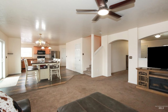 2059 Spring Creek Dr, Fruitland, ID 83619 - living area featuring arched walkways, ceiling fan with notable chandelier, dark colored carpet, and stairway