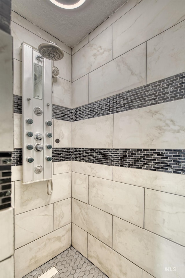 bathroom with a textured ceiling and tiled shower