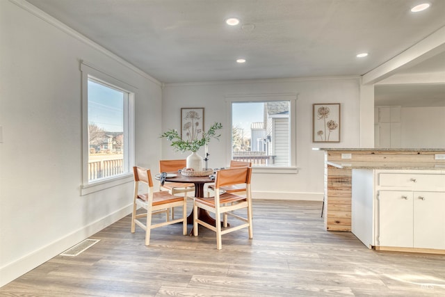 dining room with light wood-type flooring and ornamental molding