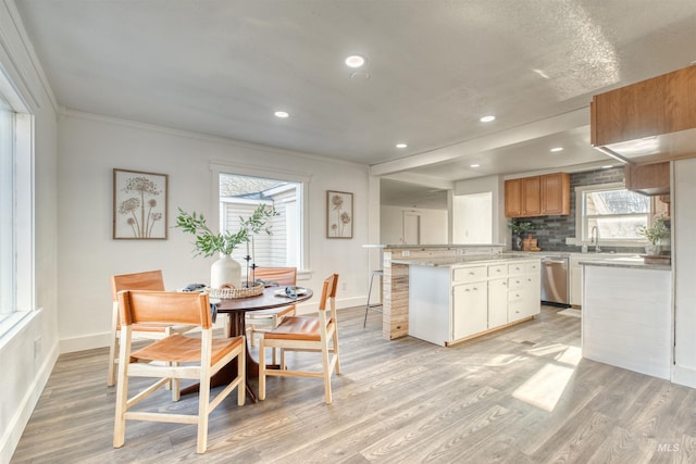 dining space with ornamental molding, sink, and light hardwood / wood-style flooring