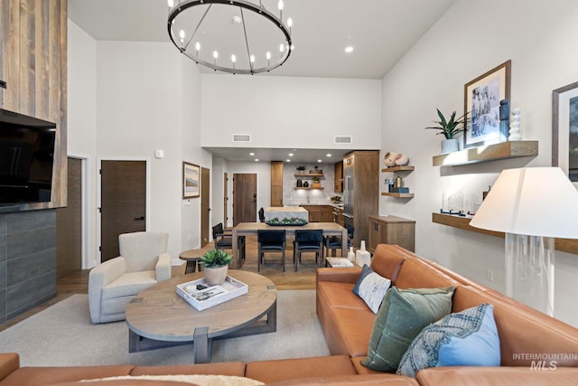 living room with a towering ceiling, wood-type flooring, and an inviting chandelier