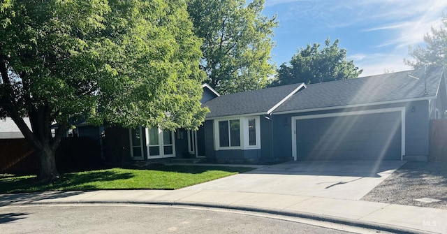 view of front of house with an attached garage, a front yard, concrete driveway, and roof with shingles