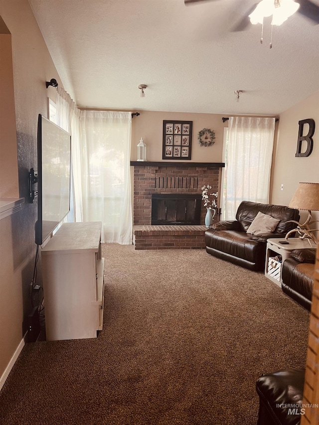 living area featuring carpet flooring, a fireplace, ceiling fan, a textured ceiling, and baseboards
