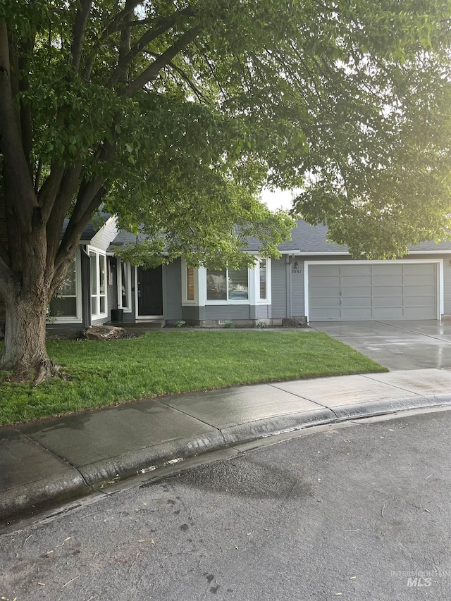 obstructed view of property featuring concrete driveway, a front yard, and an attached garage