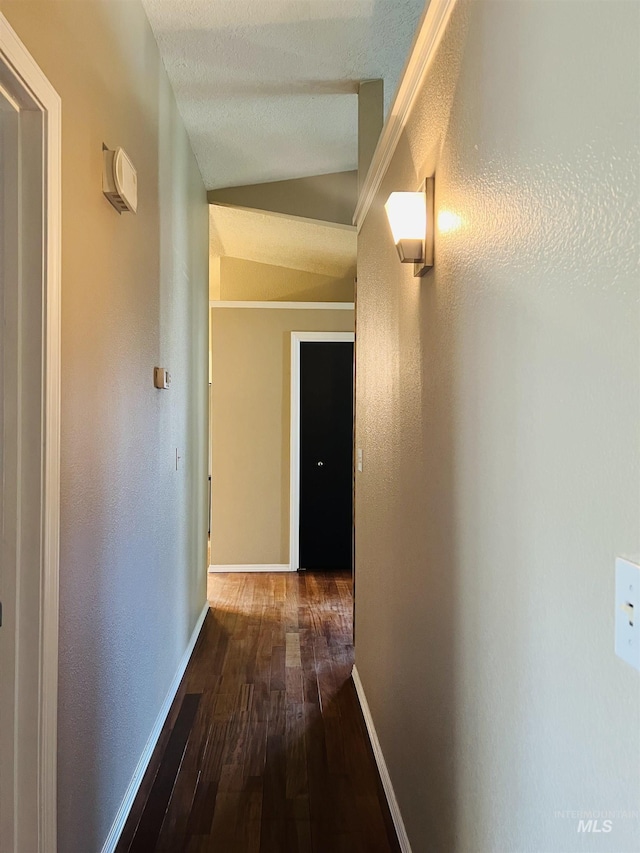 corridor featuring hardwood / wood-style flooring, vaulted ceiling, and baseboards