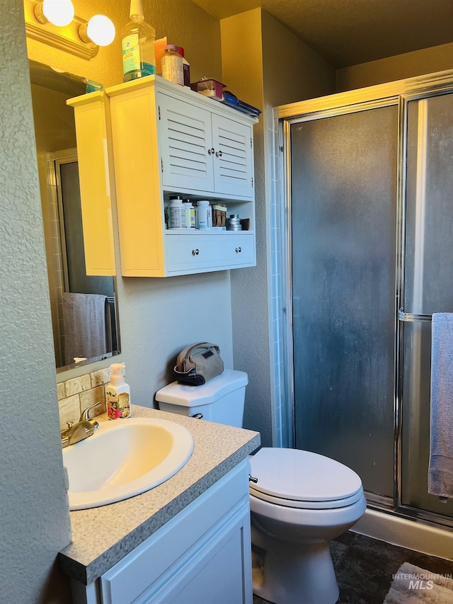 bathroom featuring a textured wall, a shower stall, vanity, and toilet