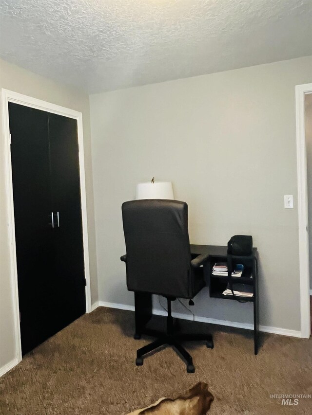 carpeted home office with a textured ceiling and baseboards