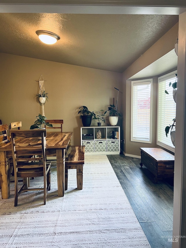 dining space featuring wood finished floors, baseboards, and a textured ceiling
