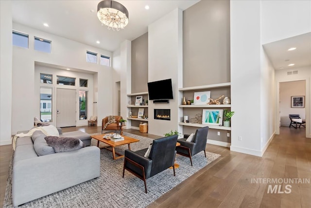 1891 E Golden Oak Ct, Meridian, ID 83646 - living area with a towering ceiling, wood finished floors, a glass covered fireplace, a chandelier, and recessed lighting