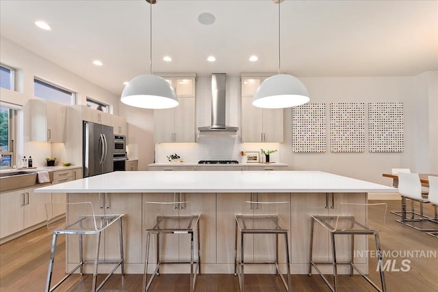 1891 E Golden Oak Ct, Meridian, ID 83646 - kitchen featuring wall chimney exhaust hood, stainless steel appliances, backsplash, a kitchen breakfast bar, and recessed lighting