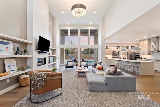 1891 E Golden Oak Ct, Meridian, ID 83646 - living area featuring light wood-style floors, a chandelier, a glass covered fireplace, recessed lighting, and built in shelves