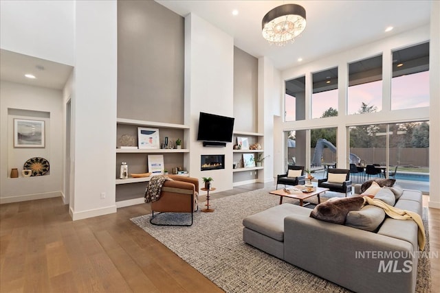 1891 E Golden Oak Ct, Meridian, ID 83646 - living room featuring a towering ceiling, baseboards, wood finished floors, recessed lighting, and a glass covered fireplace