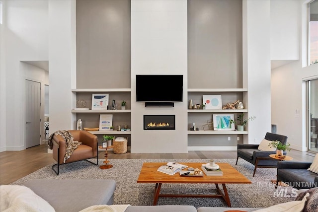 1891 E Golden Oak Ct, Meridian, ID 83646 - living area featuring a towering ceiling, wood finished floors, a tiled fireplace, built in shelves, and baseboards