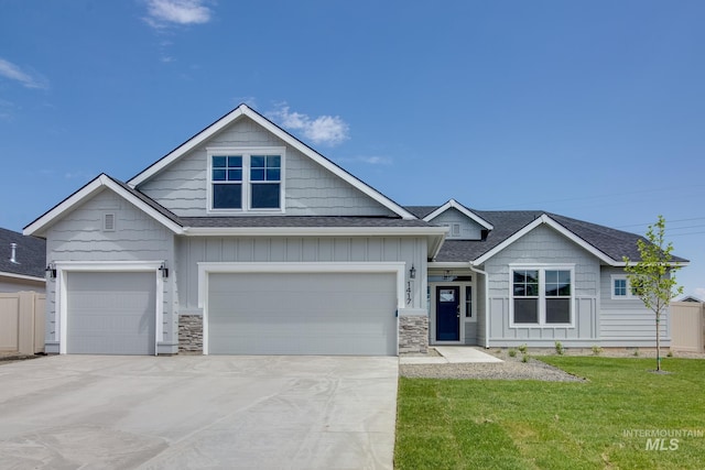 view of front of property with concrete driveway, a front lawn, board and batten siding, and a shingled roof