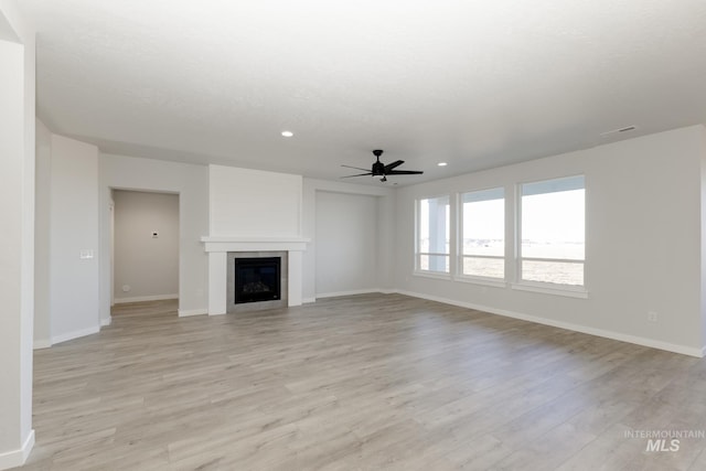 unfurnished living room with light wood-style floors, a glass covered fireplace, baseboards, and recessed lighting