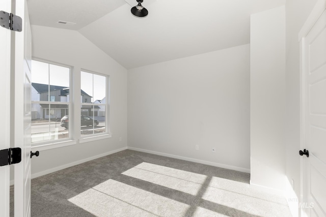 carpeted spare room featuring visible vents, baseboards, and vaulted ceiling