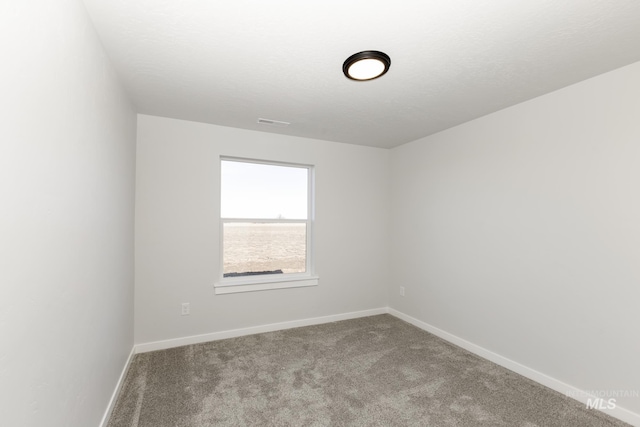 carpeted empty room with a textured ceiling, visible vents, and baseboards