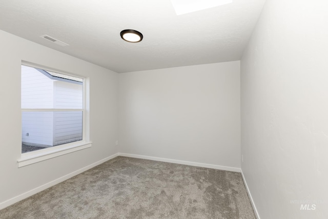 empty room with a textured ceiling, carpet flooring, visible vents, and baseboards