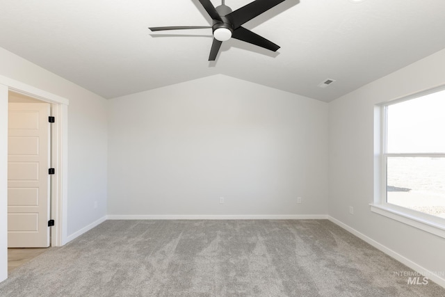 carpeted empty room featuring vaulted ceiling, a ceiling fan, visible vents, and baseboards