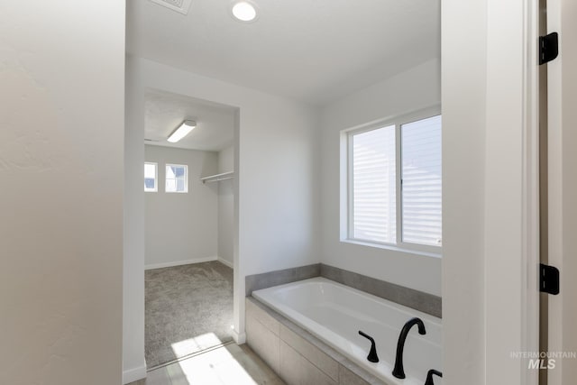 bathroom with baseboards and a bath