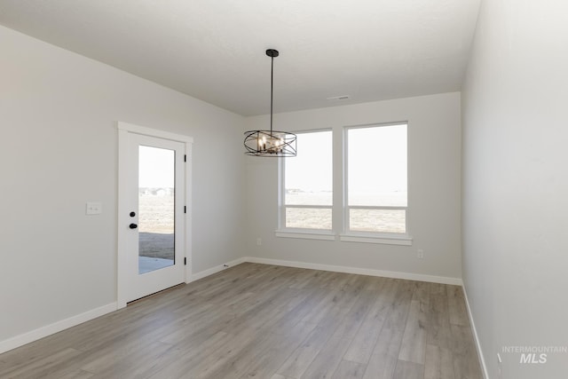 unfurnished room with light wood-style floors, visible vents, and baseboards