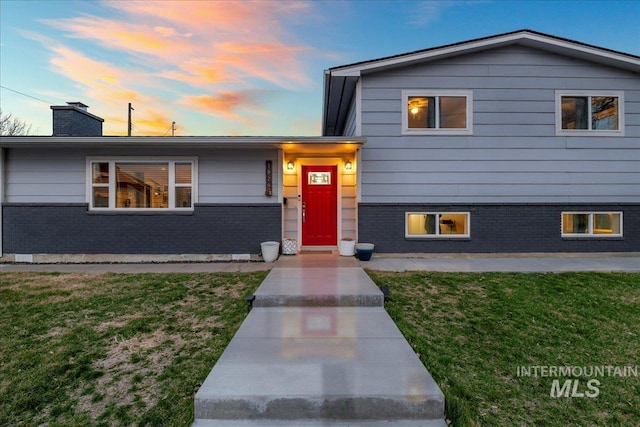 tri-level home featuring a yard, brick siding, and a chimney