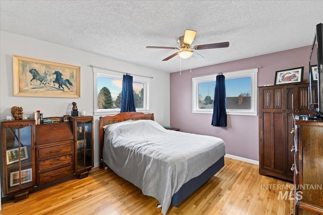 bedroom with a textured ceiling, ceiling fan, light wood-type flooring, and baseboards