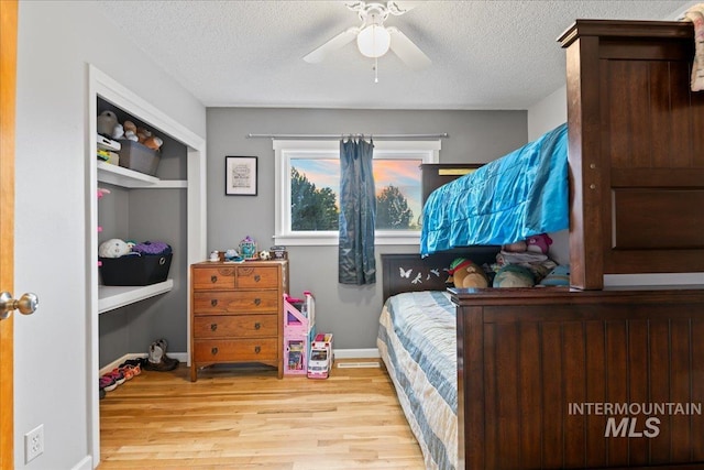 bedroom featuring a textured ceiling, baseboards, and wood finished floors