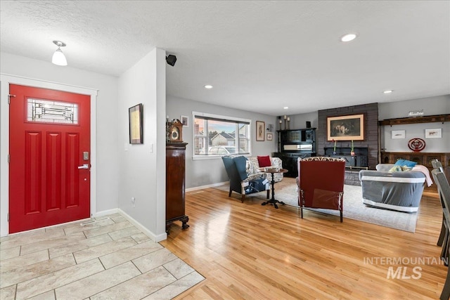 foyer featuring recessed lighting, light wood-style flooring, baseboards, and a textured ceiling