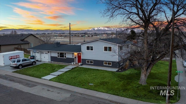 split level home with a garage, driveway, a front lawn, and a mountain view