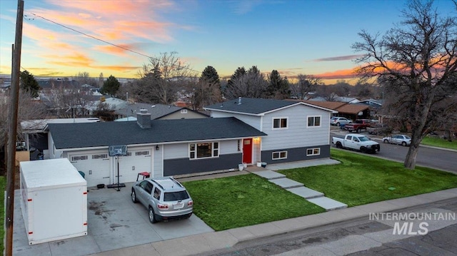 split level home with an attached garage, concrete driveway, and a front yard