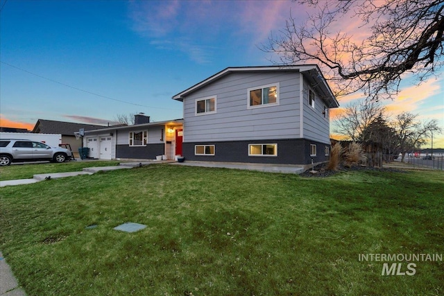 split level home with brick siding, an attached garage, fence, and a front yard