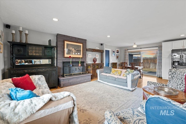 living area featuring light wood-type flooring, recessed lighting, and a wood stove