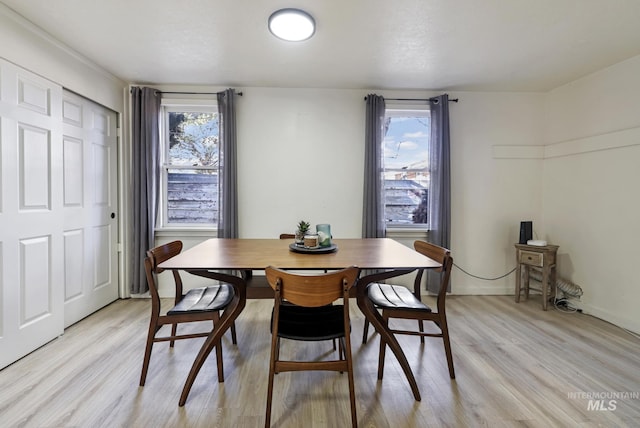 dining area featuring baseboards, light wood-type flooring, and a healthy amount of sunlight