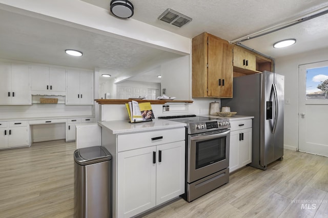 kitchen with light wood-style flooring, stainless steel appliances, visible vents, white cabinetry, and light countertops