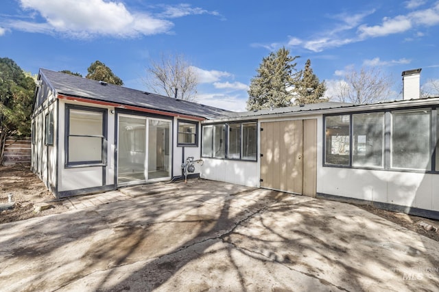 rear view of property featuring a patio area, metal roof, and a chimney