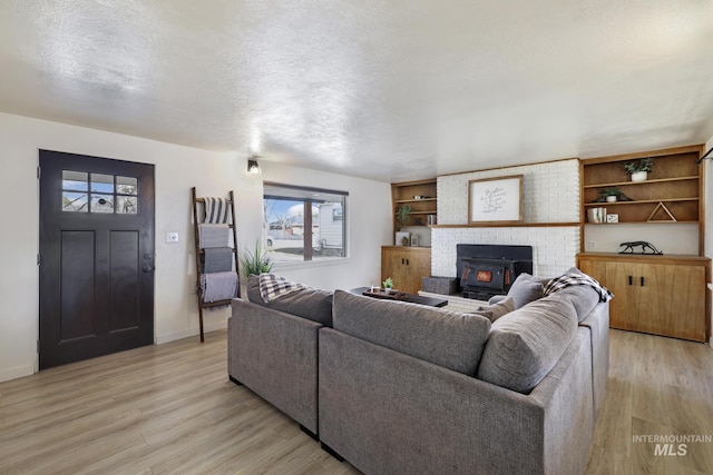 living area with light wood-style floors, a textured ceiling, and baseboards