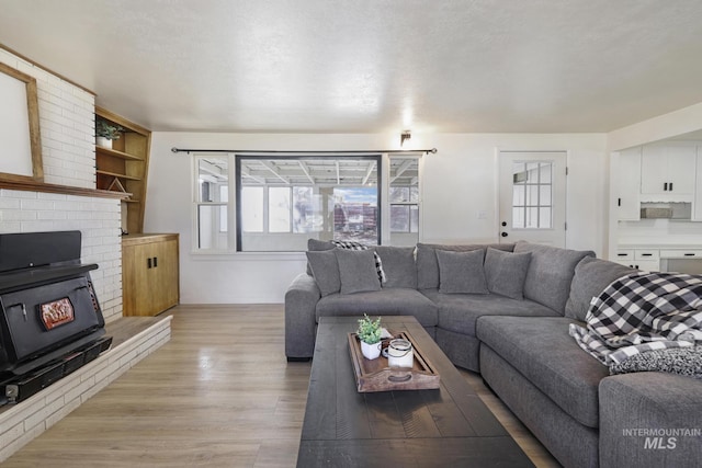 living area with a textured ceiling, light wood finished floors, and a wood stove