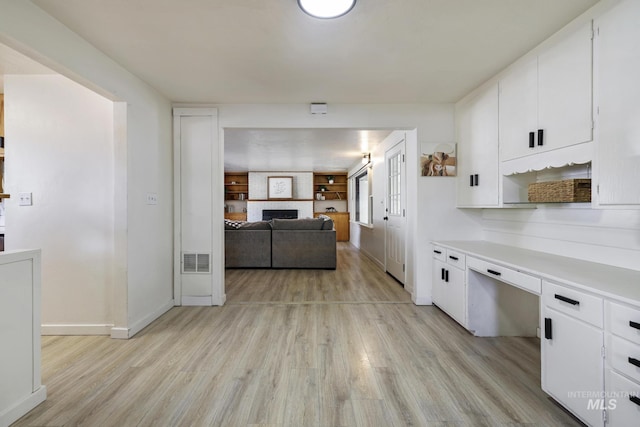 kitchen with visible vents, white cabinetry, light countertops, and built in desk