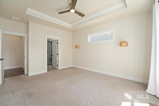 unfurnished bedroom with a tray ceiling, crown molding, carpet flooring, baseboards, and a ceiling fan