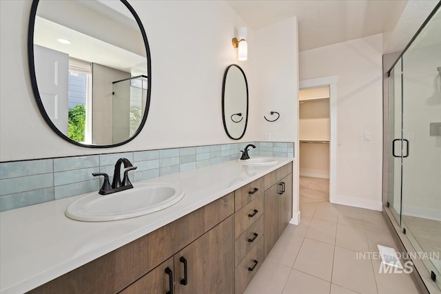 bathroom with a stall shower, tile patterned flooring, double vanity, a spacious closet, and backsplash