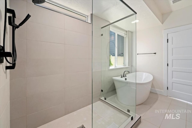 full bath featuring walk in shower, a freestanding tub, tile patterned floors, and baseboards